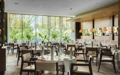 Elegancka sala restauracyjna Grand Hotel Tiffi w Iławie, z widokiem na zieleń. Stoły nakryte do posiłku, gotowe na przyjęcie gości.