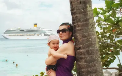Mamma e bimbo abbracciati vicino a una palma, con una nave da crociera all'orizzonte. Una splendida posizione costa pacifica.