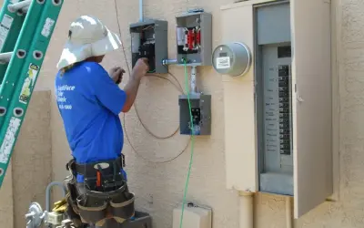Elektryk pracuje przy skrzynce elektrycznej, podłączając przewody. To kluczowy etap instalacji, który zapewni odpowiednią moc przyłączeniową.