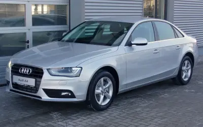Srebrne Audi A4 B8, znane z typowych usterek, stoi przed budynkiem.