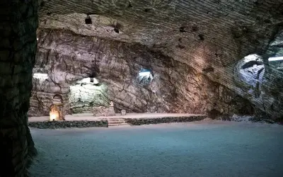 Interno della cattedrale di sale di Realmonte, con pareti rocciose stratificate e un altare illuminato.