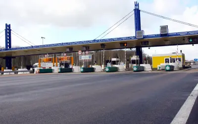 Péage d'autoroute avec plusieurs voies de passage. Une voiture attend à une borne de péage.