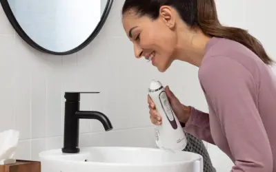 Donna sorridente impara come usare idropulsore in bagno.