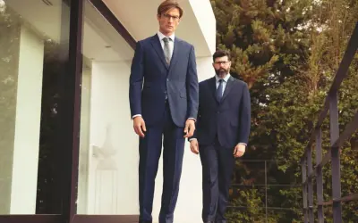 Zwei Männer in eleganten Anzügen, ein visueller anzug guide. Der vordere Mann trägt einen dunkelblauen Anzug, der hintere einen Nadelstreifenanzug.