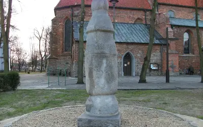 Kamienny słup milowy z inskrypcją przed ceglanym kościołem.