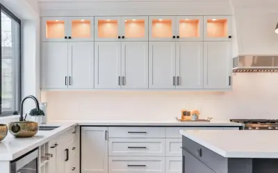 Elegante cocina moderna con gabinetes blancos, encimeras de cuarzo y detalles dorados. La iluminación cálida realza la decoración de cocinas.