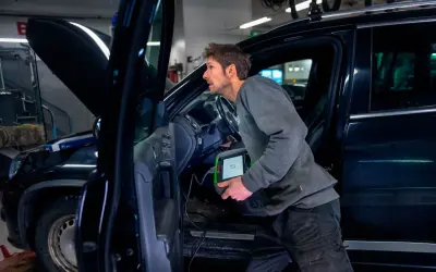 Mekaniker använder diagnosverktyg för att kontrollera bilens elektriska handbroms.