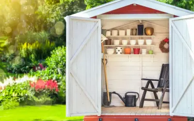 Aménagement abri de jardin : outils, pots de fleurs et chaise attendent le jardinier.