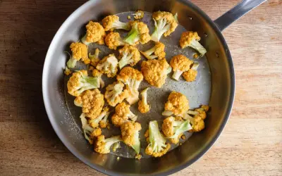 Orangefarbener Blumenkohl wird in einer Pfanne gebraten, um ihn zu kochen.