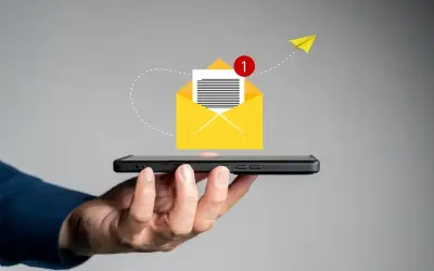 Dłoń trzyma smartfon, z którego wylatuje żółta koperta z powiadomieniem. Jak napisać SMSa o urlop na żądanie?