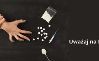 Dwie ręce walczą o kontrolę nad przedmiotami związanymi z narkotykami, w tym proszkiem, tabletkami i strzykawką. Uważaj na fentanyl.