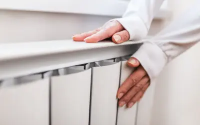 Dłonie sprawdzają ciepło grzejnika, przygotowując się na nadchodzący sezon grzewczy.