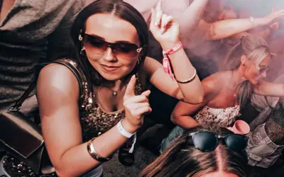 Ragazze danzano in un locale, con braccialetti "Ibiza" visibili. Un'atmosfera da festa che fa pensare al calendario eventi Ibiza.