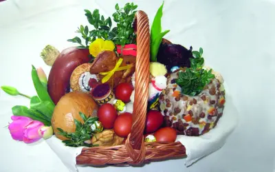 Koszyk wielkanocny z tradycyjnym święceniem pokarmów: chleb, kiełbasa, jajka, babka, zieleń i ozdoby.