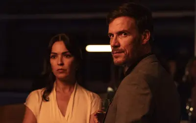 Man och kvinna i mörkt rum, en del av en psykologisk thriller topplista film. Mannen håller ett glas.