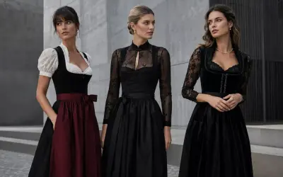 Drei Frauen in eleganten Dirndln. Das schwarze Dirndl mit Spitzenärmeln und dezentem Muster steht für moderne Eleganz.