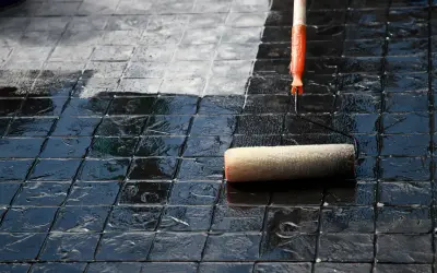 Eine Rolle versiegelt Terrassenplatten, die von dunkel glänzend zu matt wechseln.
