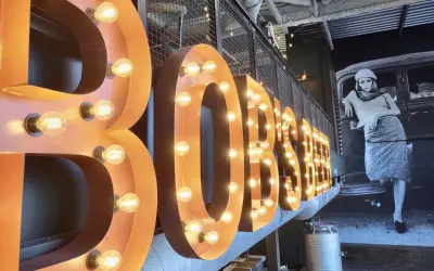 Lettre enseigne lumineuse "BOBSTER" sur fond d'une fresque vintage.