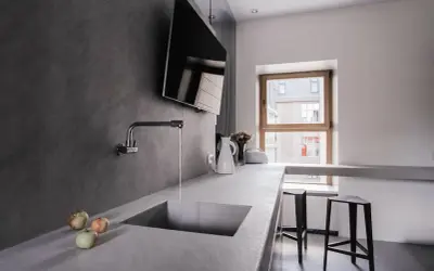 Encimera de cocina moderna con fregadero integrado de microcemento. Grifo cromado y tres manzanas sobre la superficie.
