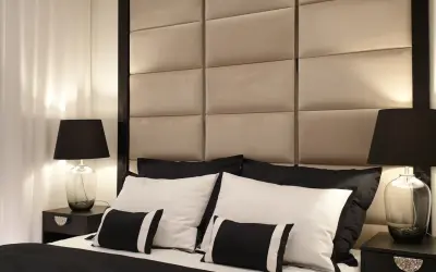 Elegancka sypialnia w stylu hotelowym. Miękkie, pikowane wezgłowie, czarno-biała pościel i stylowe lampki nocne tworzą luksusową atmosferę.