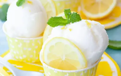 Erfrischendes Zitronensorbet-Rezept: Kugeln in gelben Tupfenförmchen, garniert mit Zitronenscheiben und Minze.