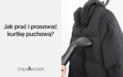 Parać i prasować kurtkę puchową parownicą Steamaster. Czarna kurtka na wieszaku, ręka trzymająca parownicę.