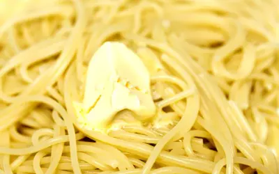 Spaghetti fumanti con una generosa porzione di burro che si scioglie, un classico piatto di pasta in bianco.