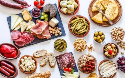 Un festin de tapas pour une pendaison de crémaillère : charcuterie, fromages, olives, cornichons, fruits secs et pain.