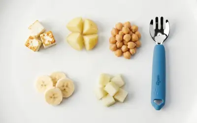 A child can eat with a fork when they master finger foods like these: paneer cubes, potato wedges, chickpeas, banana slices, and melon cubes.