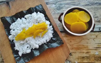 Ryż na nori, a obok miseczka z plasterkami marynowanej rzodkwi.