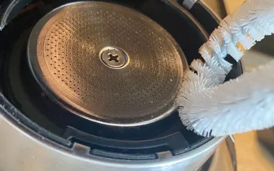 Szczoteczka czyści młynek do kawy w ekspresie DeLonghi. Drobne otwory sitka wymagają regularnego czyszczenia, by kawa była zawsze świeża.