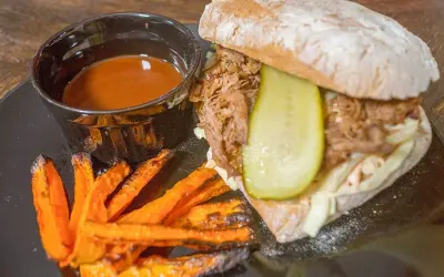 Pulled pork-macka med krispiga sötpotatispommes och en skål med smakrik sås till pulled pork.