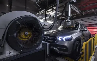 Szary Mercedes GLE na hamowni. Duży wentylator obok, a nad maską samochodu system pomiarowy. Testy silnika om647.
