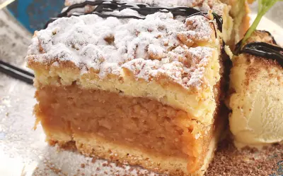Pyszna szarlotka z kruszonką, posypana cukrem pudrem, z gałką lodów waniliowych. Idealna na deser, gdy zastanawiasz się, jak zrobić jabłka do szarlotki.