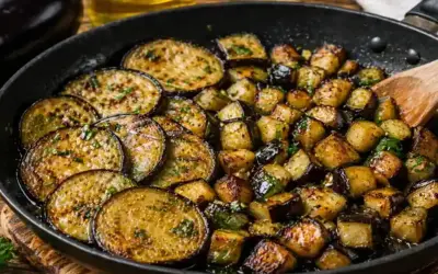 Aubergines au four, coupées en rondelles et en dés, dorées et parsemées d'herbes, dans une poêle. Un délice simple et savoureux.