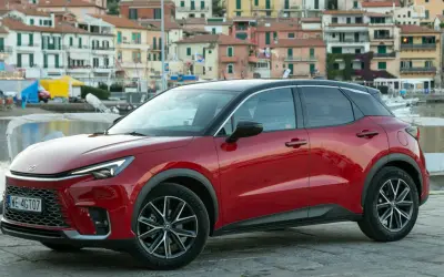 Czerwony Lexus LBX na tle nadmorskiego miasteczka. Sprawdź, jaka jest lexus lbx cena i zacznij planować wakacje!