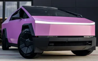 Różowy CyberTruck z futurystycznym designem i masywnymi kołami.