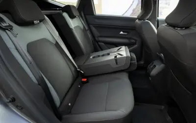 Interni Dacia Bigster: sedili posteriori in tessuto grigio e nero, bracciolo centrale ribaltabile con portabicchieri.
