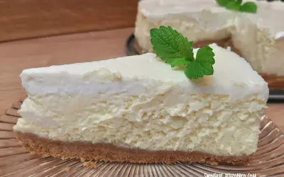 Pyszny sernik ze śmietaną kremówką, udekorowany listkiem mięty, na kruchym spodzie.