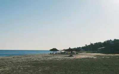 Spokojne tunezyjskie plaże z palmami i słomianymi parasolami. Idealne miejsce na relaks.