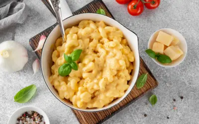 Pyszne, kremowe mac and cheese w białej misce, z bazylią i pomidorkami koktajlowymi. Idealne, gdy zastanawiasz się, jak podgrzać mac and cheese.