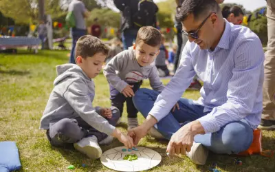 Un padre y sus hijos disfrutan de un juego en el césped, creando un momento familiar entre las tribus del parque Zaragoza.