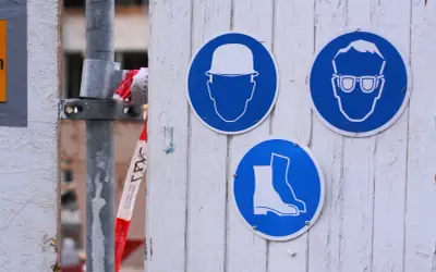 Znaki BHP przypominają o obowiązkach pracodawcy: kask, okulary i obuwie ochronne to podstawa bezpieczeństwa na budowie.