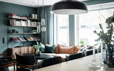 Vardagsrum med bokhylla i 50-talsstil, soffa i läder och stora fönster.