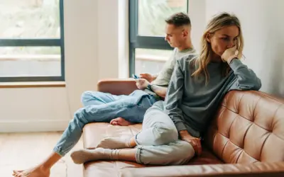 Een vrouw denkt diep na, terwijl een man op zijn telefoon kijkt. Het lijkt erop dat opposites attract betekenis hier niet opgaat.
