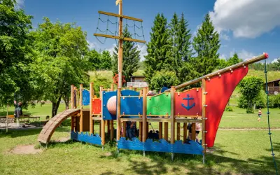 Kolorowy plac zabaw w kształcie statku pirackiego, oferujący mnóstwo atrakcji dla dzieci w Brzegu. Idealne miejsce na letnie zabawy.