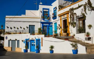 Casas blancas con puertas y ventanas azules, un ejemplo de lo que ver cerca de Níjar. Plantas en macetas adornan las fachadas.
