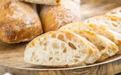 Frisch gebackene Ciabatta-Brote, aufgeschnitten auf einem Holzbrett. Das luftige Innere und die knusprige Kruste sind perfekt für ein Ciabatta Rezept.