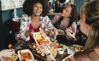 Vier Freundinnen genießen einen köstlichen Brunch in Berlin. Sie lachen und teilen sich Speisen wie Garnelen und Pommes.