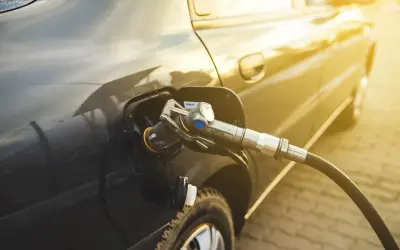 Tankowanie auta gazem. Złoty promień słońca odbija się od lakieru, gdy pistolet LPG jest włożony do wlewu paliwa. Sprawdzamy aktualną cenę LPG.
